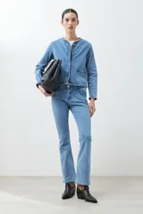 Chaqueta de jean celeste con cuello redondo, cierre con botones metálicos y detalle trenzado en cuello, bolsillos y ruedo.