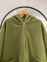 Tapado largo verde oliva con capucha, cierre frontal con cremallera y bolsillos delanteros.