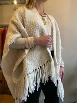 Ruana color crema tejida en lana merino con flecos.