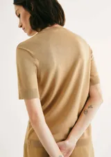 Blusa color beige de tejido de punto, con cuello redondo y mangas cortas.