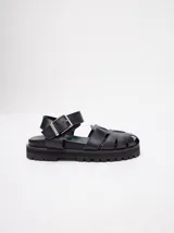 Sandalias romanas color verde oliva, con tiras entrecruzadas y hebilla lateral. Suela de goma negra con plataforma de 3cm. Fabricadas en cuero vacuno.