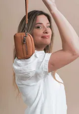 Monedero negro de simil cuero con correa para la mano, diseño práctico y compacto. Bolsillo principal con doble cierre, y un bolsillo frontal pequeño para llevar monedas.