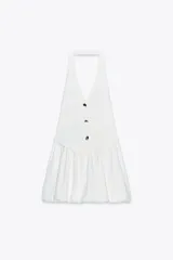 Minivestido blanco con corte tipo chaleco, cuello halter, escote en V y botones negros. La falda es corta y abullonada.