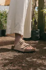 Sandalia de gamuza color beige con doble tira, tachas y hebillas metálicas.