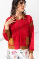 Chaqueta estilo bomber tejida color marrón con detalles en beige, cierre frontal y bolsillos delanteros.