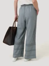 Pantalón gris de lino y viscosa con ajuste elástico y cordón en la cintura. Presenta broderie tono a tono en los laterales y en la parte inferior.