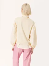 Sweater color crema de tejido de punto fino, con cuello redondo y mangas largas abullonadas.