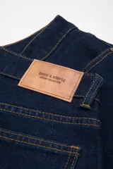 Pantalón jean azul oscuro, corte mom fit, con bolsillos delanteros y traseros, y terminación arremangada.
