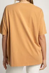 Remera color ocre de corte oversize, con estampado de flores y texto en francés.