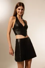 Top negro de cuero sintético con escote halter, corte al cuerpo y cierre frontal con alamares.