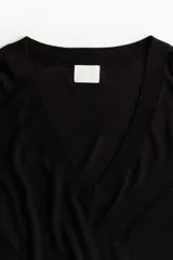 Sweater negro de punto fino, con escote en V pronunciado, corte holgado y hombros caídos.