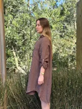 Vestido camisero blanco de lino, con cuello camisero, manga larga con botón para recoger, cierre frontal con botones de nácar, bolsillo en el pecho y diseño asimétrico más largo en la parte trasera.