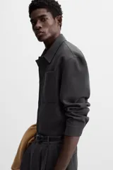 Sobrecamisa verde oscuro de corte cuadrado, con cuello solapa, manga larga con puños abotonados, bolsillos de parche en el pecho y bolsillos laterales en la cadera. Cierre frontal con botones.
