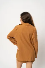 Blazer marrón claro a rayas verticales, con solapas de muesca, cierre con doble botonadura y corte holgado.