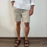 Bermuda color verde militar, de corte recto y largo a la rodilla, con cintura ajustable con cordón y bolsillos laterales. Confeccionada en simil lino.