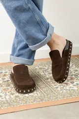 Zuecos negros de cuero gamuzado, con detalle de tachas plateadas en la base y plantilla con logo estampado.