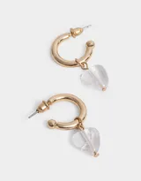 Aros dorados tipo argolla con dije colgante de cristal transparente en forma de corazón.