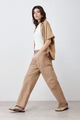 Pantalón de gabardina color tostado, de corte recto, con bolsillos laterales y traseros. Se ajusta a la cintura con cinturón de cuero con estampado animal print.