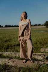 Conjunto de top y pantalón color beige. El top es de breteles anchos, con detalle en dos colores y un bordado en su delantera. El pantalón es liso, de corte recto ancho con bolsillos a los costados y cintura con botones y elástico.