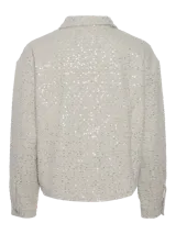 Chaqueta color crema con lentejuelas, cuello camisero, cierre frontal con botones y mangas largas.
