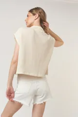 Camiseta negra con textura acanalada, corte holgado y cuadrado, cuello en punta, bolsillos amplios y botones funcionales.