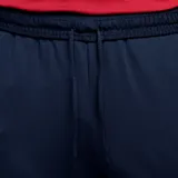 Pantalón largo de fútbol Nike FC Barcelona Strike para hombre, color azul marino con detalles en naranja. Presenta el escudo del club y el logo de Nike bordados.