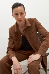 Camisa de manga larga color tostado, con cuello camisero y botones frontales. Presenta bolsillos de parche en el pecho.