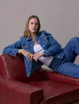 Campera de jean azul de la marca Baccini, con cuello solapa, abertura central con botones metálicos, bolsillos delanteros y ruedo desflecado.