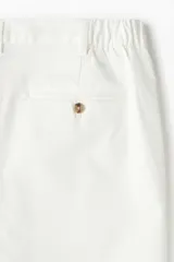 Short blanco de sarga de algodón suave, con elástico en los laterales de la cintura, cierre con botón, bolsillos al bies y bolsillos de atrás ribeteados con botón.