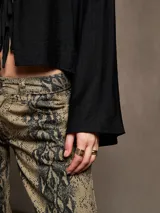 Pantalón de jean con estampado de piel de serpiente en tonos beige y negro, corte recto.