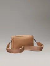 Bandolera Calvin Klein color marrón claro con estampado del logo de la marca. Tiene correa ancha ajustable, cierre de cremallera, bolsillo exterior delantero y bolsillo interior.