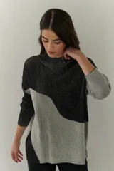Buzo de punto con diseño geométrico en bloques de color gris y negro, de cuello redondo y mangas largas.