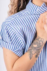 Camisa celeste a rayas verticales blancas, de lino y corte holgado.