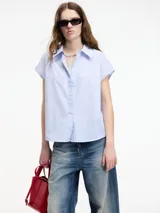 Camisa sin mangas a rayas verticales celestes y blancas, con botones en la parte delantera y trasera, y cuello camisero.