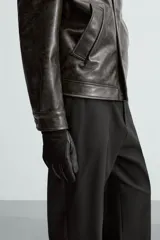 Pantalón negro de corte recto, con cintura elástica y cierre frontal de cremallera y botón. Presenta bolsillos delanteros y bolsillos traseros de vivo.