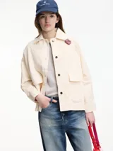 Chaqueta color crema con bordados florales y apliques de pedrería. Tiene cuello camisero, cierre frontal con botones, bolsillos laterales y corte recto.