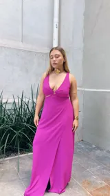 Vestido largo fucsia con escote en V con aro y falda en capas diagonales.