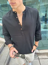 Camisola negra de lino con cuello mao y mangas largas con puños abotonados. Cierre frontal con botones de madera.