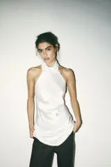 Vestido corto blanco de satén con cuello halter y espalda descubierta.