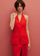Chaleco rojo de lino con cuello halter, sin mangas, corte entallado, cierre frontal con botones y dos bolsillos de solapa laterales.