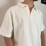 Chomba negra de corte oversize con cuello polo y tapeta de dos botones. Tejido de punto acanalado vertical.