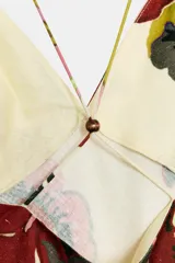 Vestido midi con estampado floral, escote en pico y tirantes finos ajustables con detalle de abalorios de madera. Cierre lateral con cremallera oculta.