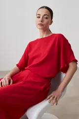 Blusa roja de manga corta con volados en los puños y cuello redondo.