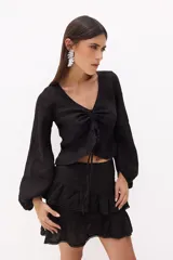 Top blanco de lino italiano con escote en V, mangas largas estilo globo y jareta ajustable en la parte delantera que crea un efecto fruncido y volado en el ruedo.