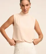 Blusa color crema de poliéster satinado, con cuello alto, sin mangas y botón en la nuca.