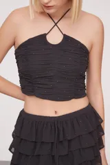 Top gris oscuro sin mangas con diseño ajustado y detalles de fruncido.