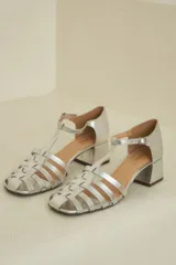 Sandalias plateadas de cuero acharolado con puntera calada, pulsera ajustable y taco cuadrado.
