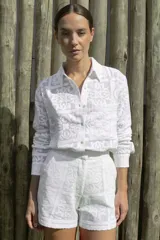 Camisa blanca con textura de encaje, de corte recto, manga larga y cuello camisero.