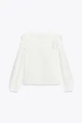 Camisa blanca de popelín de algodón con cuello redondo con tejido en superposición a tono y aplicación de bordados. Manga larga acabada en elástico y cierre frontal con botones ocultos por sopata.