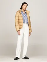Campera puffer color beige, con capucha y cierre frontal con cremallera. Tiene dos bolsillos delanteros con botón a presión y parche con el logo de Tommy Hilfiger en la manga.